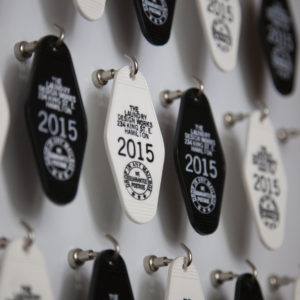 Close up of a bunch of retro style motel keychains imprinted with Laundry graphics hanging from hooks on a wall